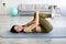 Happy fit Indian woman stretching her lower back on yoga mat, hugging her knees, doing domestic sports indoors