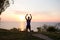 Happy fit runner watching sunrise or sunset with rised fists, young athlete on grass during the sunrise in the sea