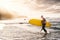 Happy fit senior surfing on sunset time - Sporty mature man having fun training with surfboard in ocean