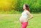 Happy fitness pregnant smiling woman enjoys sunny summer
