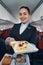 Happy flight hostess offering meal from catering trolley