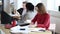 Happy focused business woman in red dress very busy with paperwork, writing on documents at modern office table.