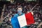 Happy football fan with face mask holding national flag of France cheering his favorite soccer team at international sport event