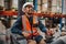 Happy forklift driver focused on carefully transporting stock from shelves around the floor of a large warehouse wearing