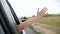 Happy free girl put her hand out and in the car window. concept travel road hand out of the window. the girl touches the
