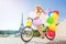 Happy French girl cycling with colorful balloons