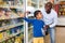 Happy friendly African family of father and tween son shopping together in supermarket