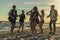 Happy friends dancing on the beach. Men is playing guitar