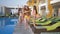 Happy friends on summer holiday, cheerful group of attractive long haired girls in swimsuits stroll by pool and lounger