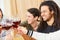 Happy friends toast together with glass of red wine at celebration