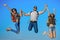 Happy friends, tourists jumping on mountain top on blue sky. Summer vacation. Traveling and hiking.