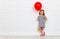 Happy funny child girl with red ball near an brick wall