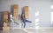 Happy funny couple holds cardboard boxes for moving in new apartment house room