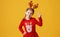 Happy funny emotional child girl in red Christmas reindeer costume  on yellow   background