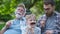 Happy funny family son and dad, granddad with fake mustache, hat, eyeglasses on holiday outdoor in park. Good day