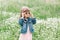 Happy funny little cute girl in sunglasses on the field with daisies. Sunny day outside