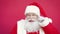 Happy funny Santa Claus touching mustache looking at camera on red background.