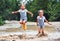 Happy funny sisters twins child girl jumping on puddles in rub