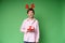Happy funny teenager boy in red christmas deer costume in light shirt with gift