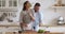 Happy funny young couple joking while preparing salad in kitchen