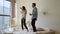 Happy funny young family couple dancing jumping on bed mattress