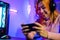 Happy Gamer playing video game online with smartphone with neon lights