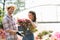 Happy gardeners holding flower pot outside greenhouse