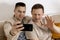 Happy gay couple with casual clothes holding smartphone and talking with friends online, having video call. Homosexual