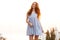 Happy Ginger girl in dress posing on the sunset