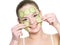 Happy girl applying facial mask of cucumber