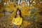 Happy girl in autumn forest with yellowing leaves