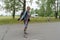 Happy girl backpacker stands with a backpack on the road, against the background of trees on a summer day