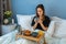 Happy girl in bed with wooden tray with tasty breackfast