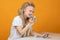 Happy girl bites off  banknote, crumpled money in hands sitting at  white table