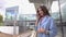 Happy girl in blue coat talking on her mobile phone at train station. 4K shot