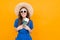 Happy girl in a blue dress and a straw hat and sunglasses with a passport and vacation tickets on a yellow background