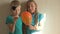 Happy girl in a blue T-shirt blows bright balloon in bathroom at home. Blond boy with needle pierces a balloon. shallow focus