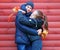 A happy girl and boy posing near red wooden wall and enjoys autumn