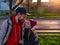 Happy girl with braided hair and father in spring park sits on a bench on sunset outdoor.Kid with dad smiling having fun