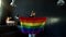 Happy girl celebrates LGBT freedom and support with rainbow flag in a dark room