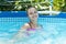 Happy girl child enjoy swimming in leisure pool on sunny summer day, vacation