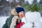 Happy girl child plaing with a snowman on a snowy winter walk