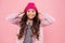 Happy girl child smile with beauty look and long brunette hair fixing fashion beanie hat on head pink background, autumn