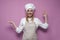 Happy girl cook in apron shows okay hand and smiles on a colored background, cheerful woman housewife in kitchen clothes