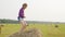 Happy girl dancing on haystack at harvesting field. Cheerfullteenager girl dancing on hay stack in countryside. Young