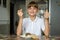 Happy girl at the dinner table holds a pill in one hand, a glass of water in the other