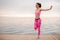 Happy girl doing stretch exercises on the sunrise on the seaside