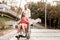 Happy girl enjoying hot coffee and calm man pushing her wheelchair