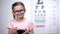 Happy girl in eyeglasses holding bowl with blueberries, natural vitamins, vision