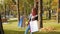 Happy girl with foxy hair dancing in the park with purchases in multi-colored paper bags and rejoices